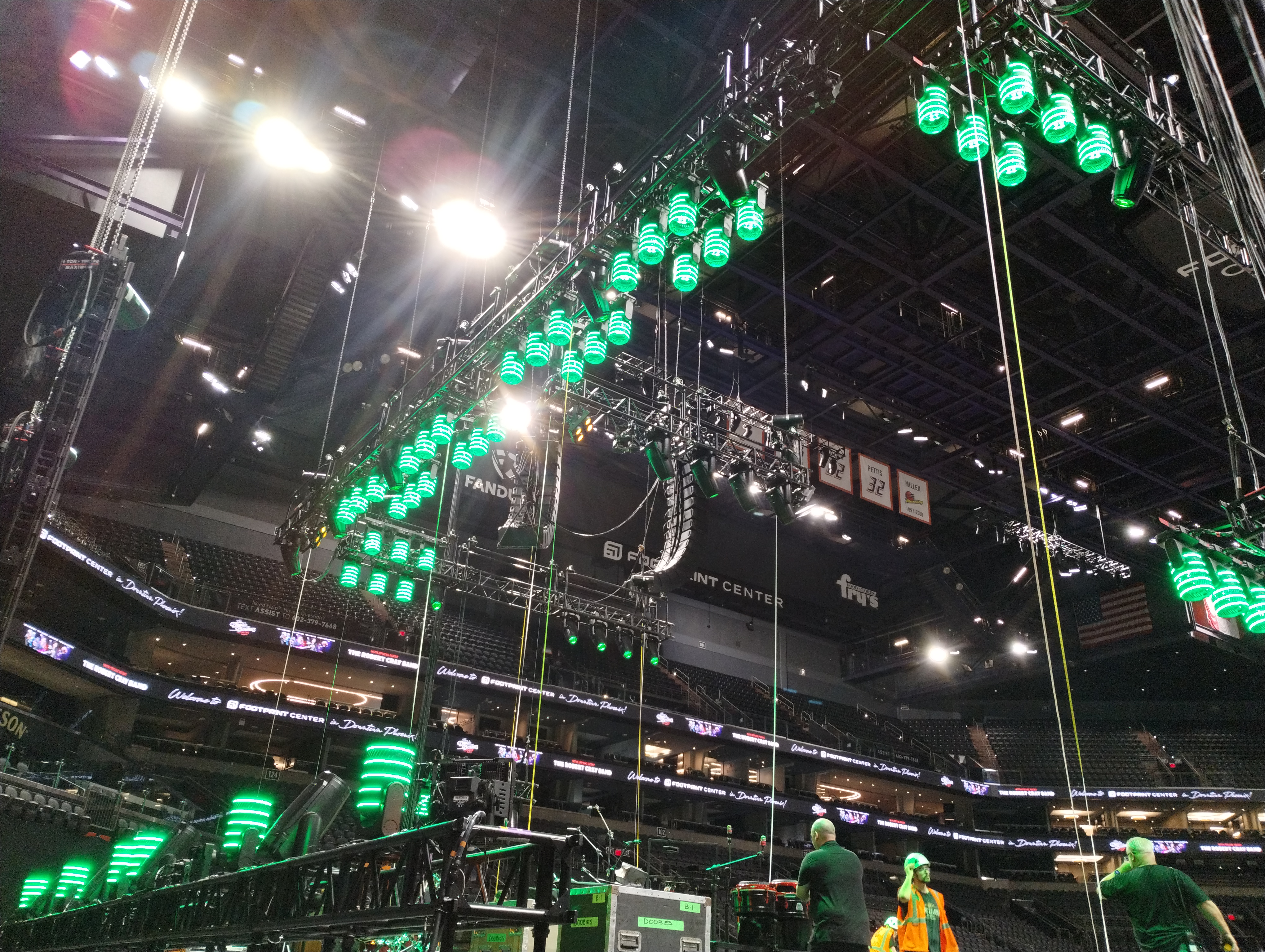 Production lighting rig with green moving fixtures being flown at Mortgage Matchup Center during load-in