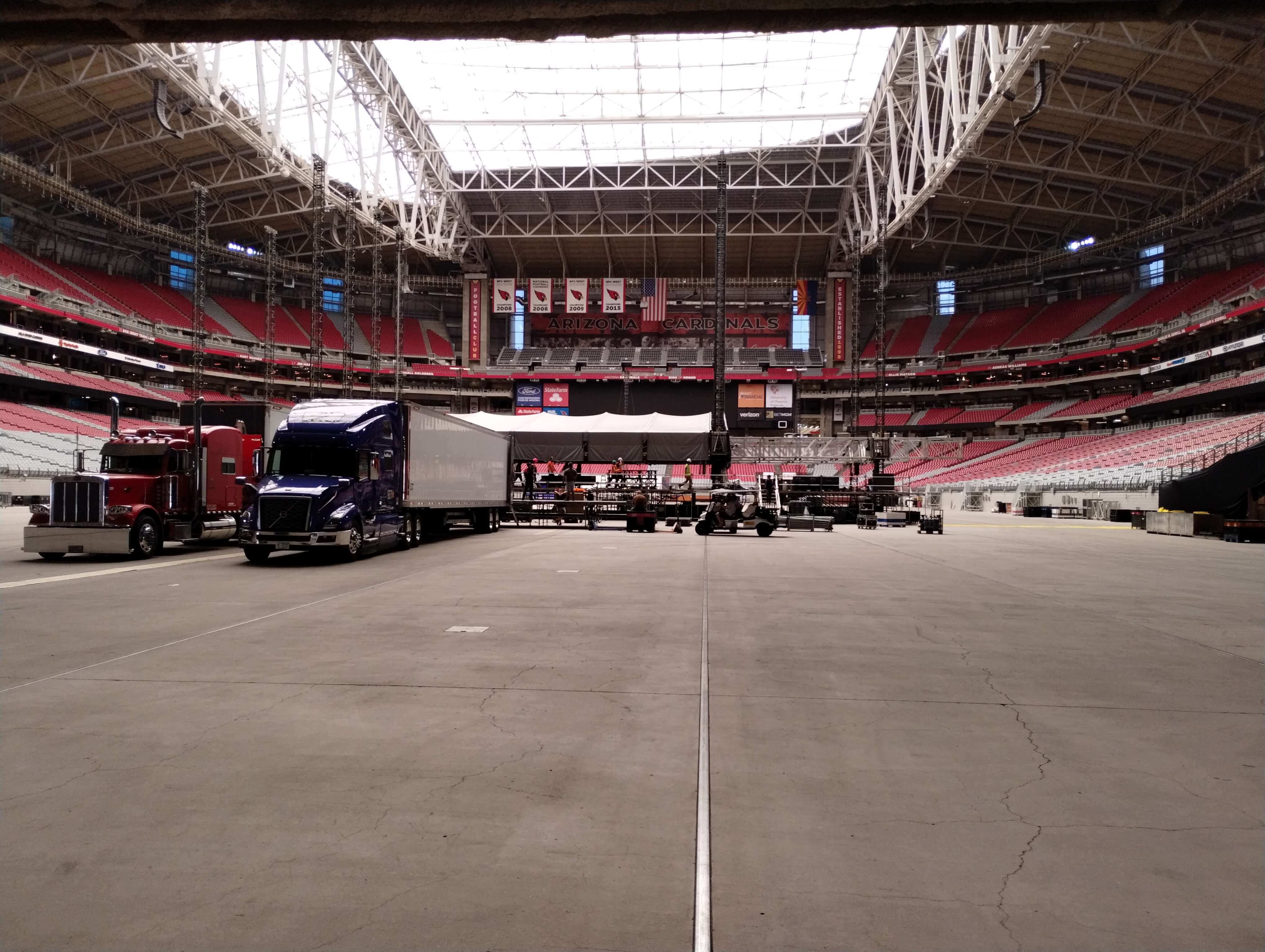 Semi-trucks parked on the floor of State Farm Stadium during large-scale concert production load-in