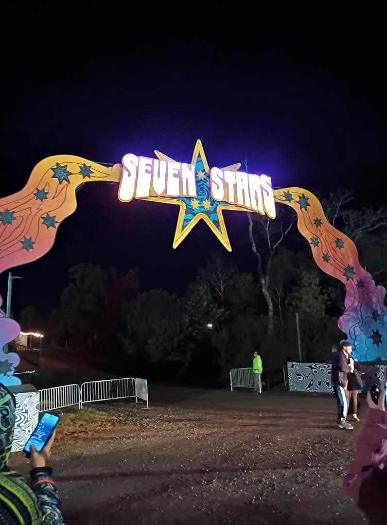 Illuminated Seven Stars scenic entrance arch at Electric Forest glowing against a night sky
