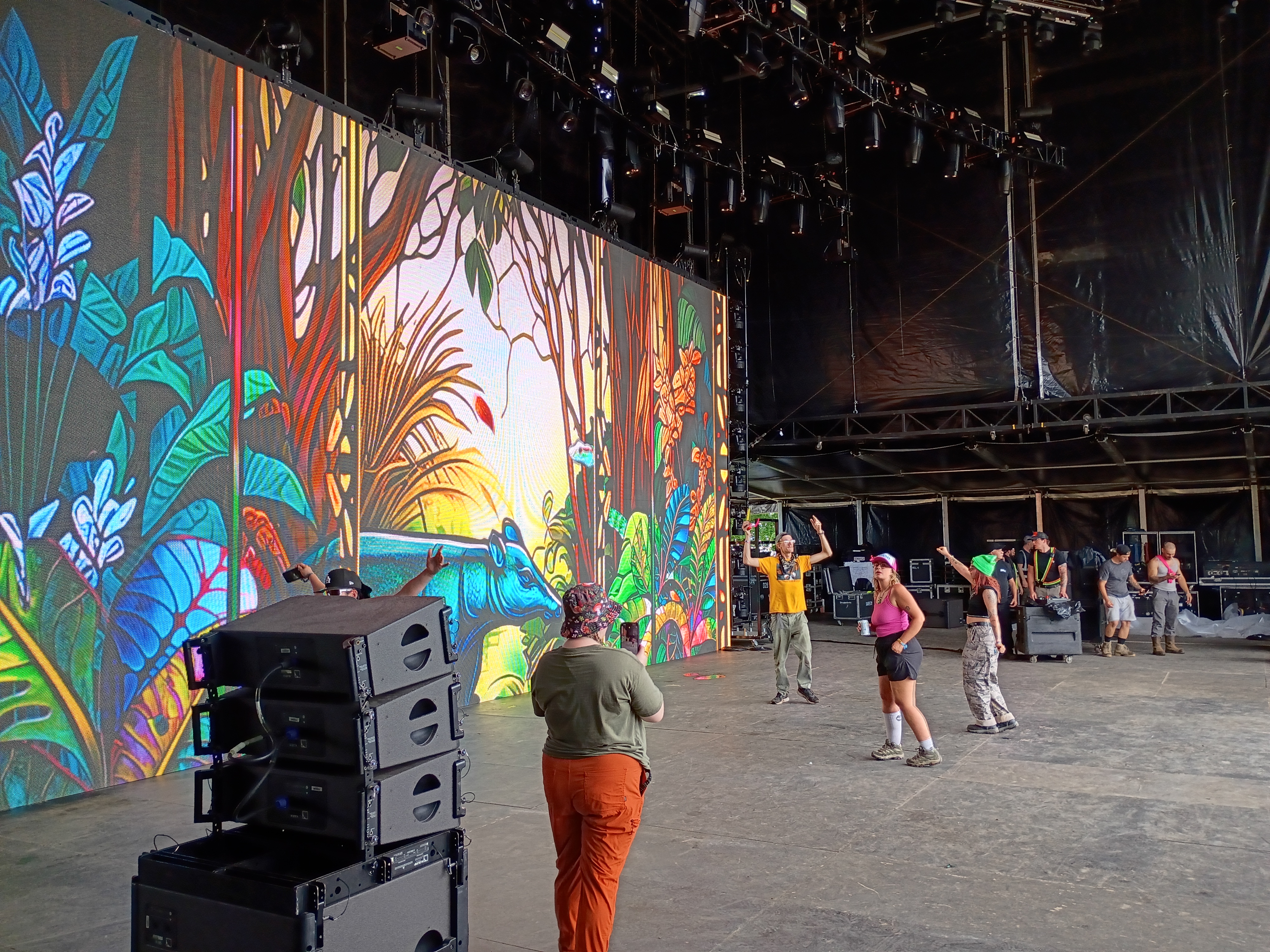 Crew on stage floor in front of a large jungle-themed LED video wall at Sherwood Court, Electric Forest