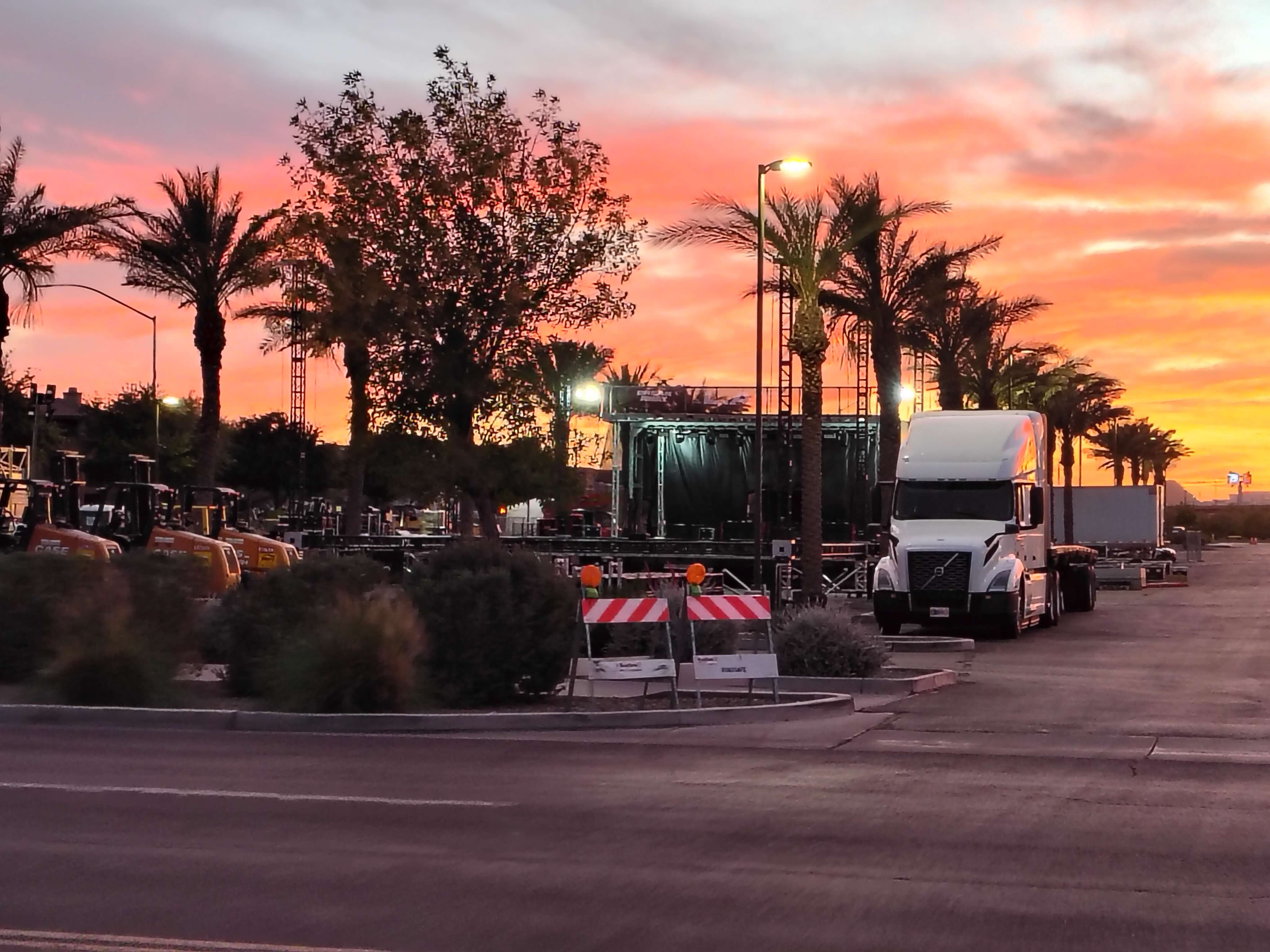 Production truck and stage truss towers silhouetted against a vivid Arizona sunset during Breakaway Mesa festival build week