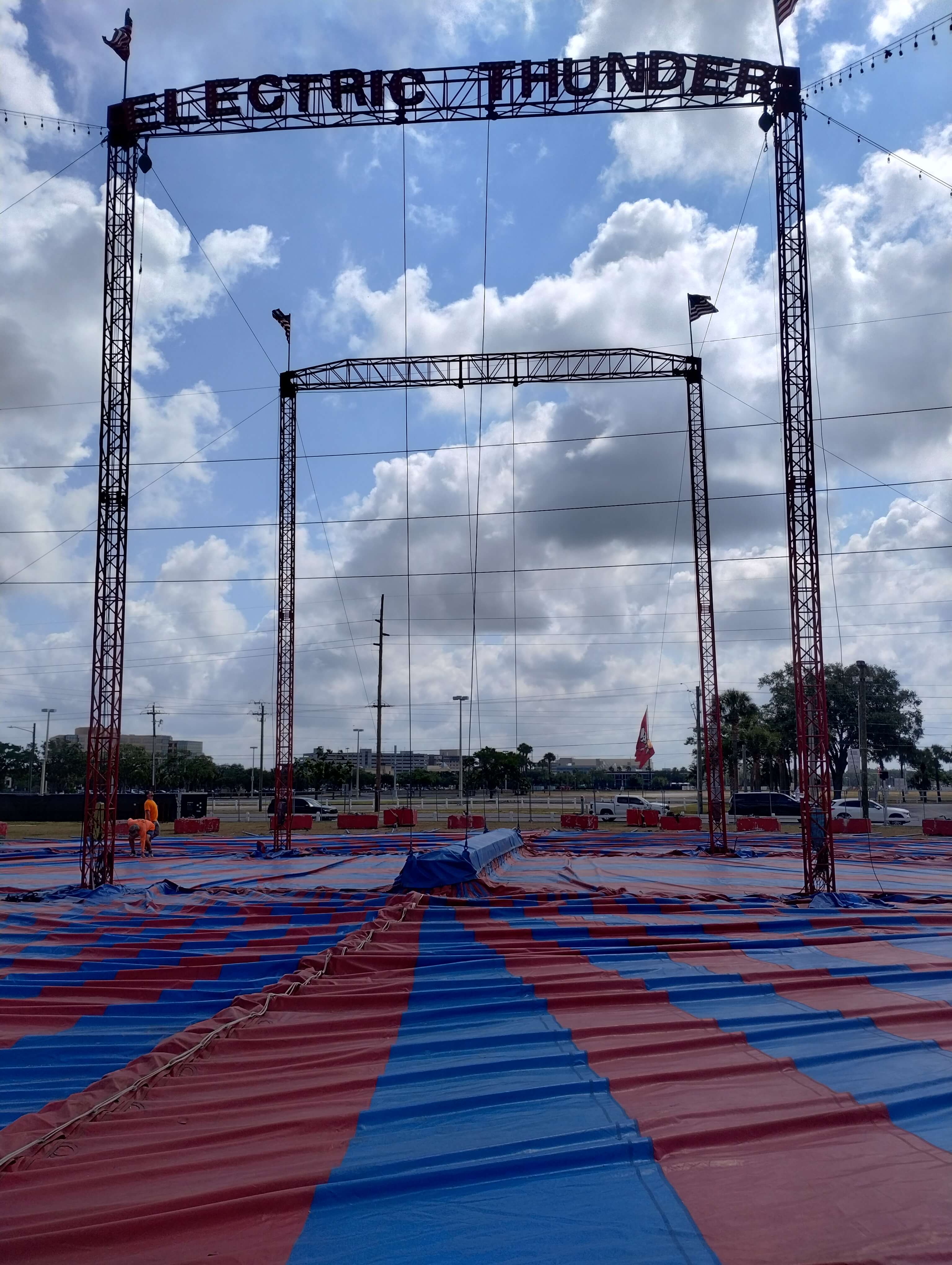 Electric Thunder tent truss arch at Country Thunder with red and blue tent canvas laid out on the ground during setup