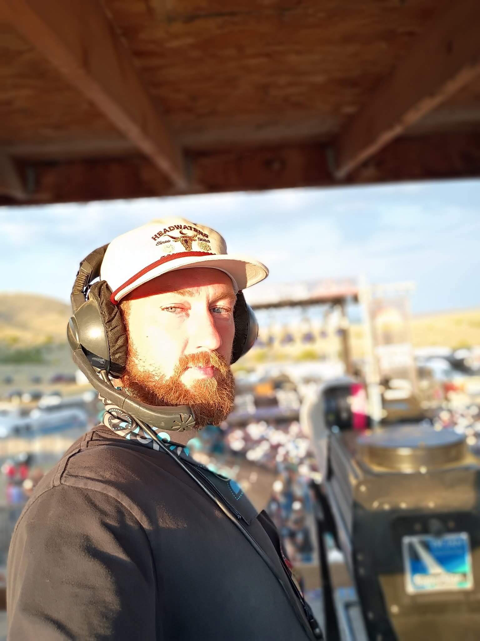 Aaron Bowman operating followspot in headset and cap at Country Jam Montana 2025 with crowd and stage below